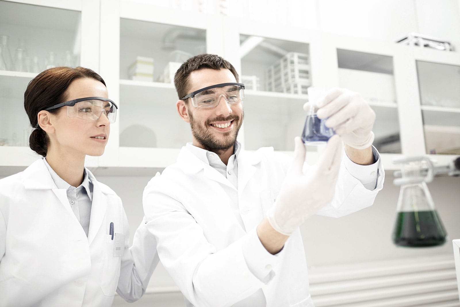 Female and male researchers in a lab holding beaker