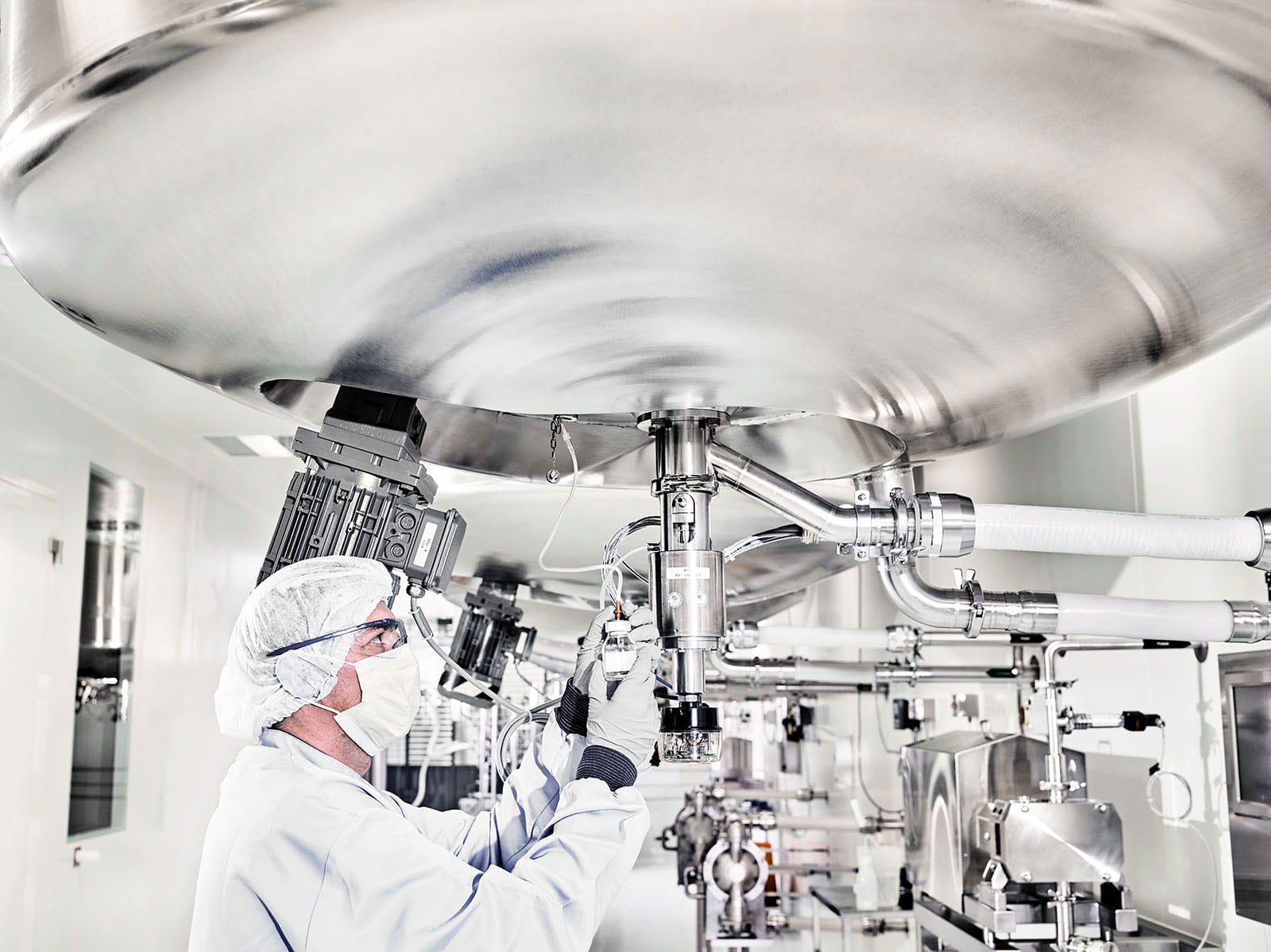 Gowned employee inspecting Bern manufacturing tanks