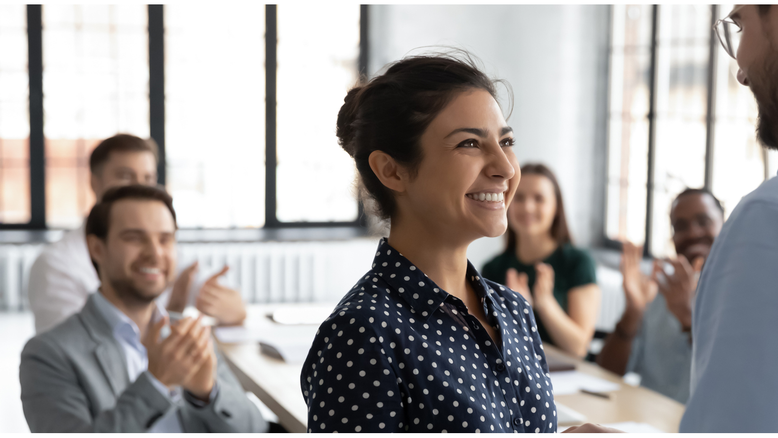 Picture of smiling people in an office. A lady and man are shaking hands.
